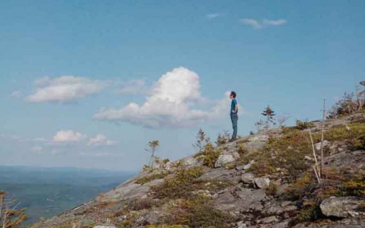 a person stands on a rock on a lookout spot in maine on an outward bound trip